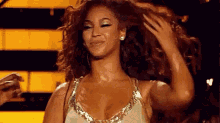 a woman with long curly hair is standing on a stage and touching her hair .