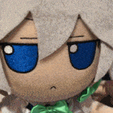a stuffed doll with white hair and blue eyes has a green bow tie