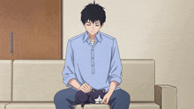 a man is sitting on a couch petting a black cat