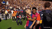a group of soccer players are hugging each other on a field with a score of 5 to 3 in the background