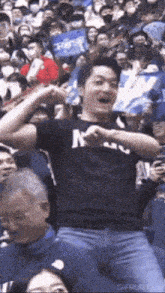 a man wearing a black shirt with the letter m on it is dancing in a crowd