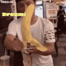 a man in a white shirt is holding a large yellow object in front of his face