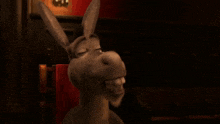 a donkey is standing in a dark room in front of a red chair .