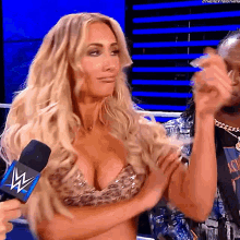 a woman in a very revealing top is being interviewed by a man holding a microphone with a w on it
