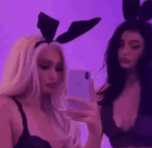 two women in bunny ears are taking a selfie with their cell phones .