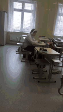 a woman wearing headphones sits in a classroom
