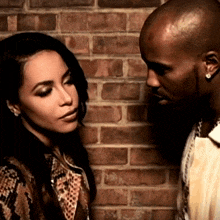 a man and a woman standing next to each other in front of a brick wall