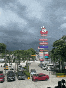 a large jollibee sign is in the middle of a parking lot surrounded by cars