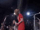 a woman wearing a fox mask sings into a microphone on stage