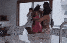 a group of women are fighting in a kitchen in front of a sliding glass door .