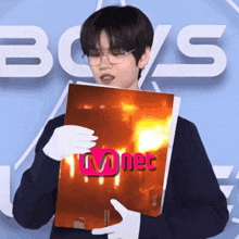 a man in white gloves holds a book that says mnet on it