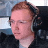 a young man wearing headphones and glasses is looking at the camera .