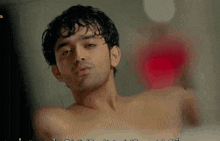 a man without a shirt is taking a bath in a bathtub .