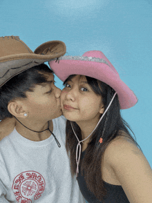 a man kisses a woman on the cheek while wearing a cowboy hat