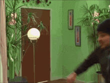 a man in a black hat is standing in a green room