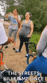 a group of people are riding bicycles down a dirt road and talking .