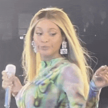 a woman with long blonde hair is holding a microphone and making a face .