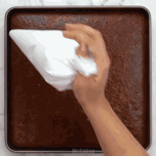 a person is frosting a brownie in a pan that says mrs. cakes