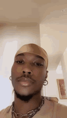 a man with a beard and earrings is wearing a headband and a necklace .