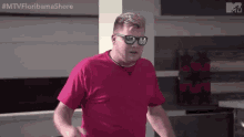 a man wearing a pink shirt and sunglasses is standing in a room .