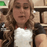 a woman in a black shirt is holding a jar of ice cubes .