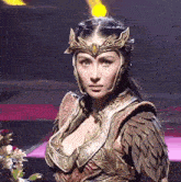 a woman wearing a helmet and armor is standing on a stage