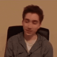 a young man is sitting in a chair and making a face .