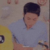 a man in a blue shirt is sitting at a table with a birthday cake .