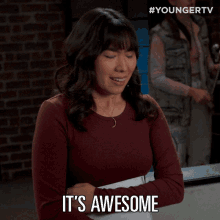 a woman says it 's awesome in front of a brick building
