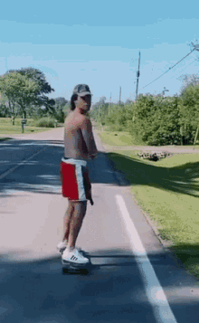 a man without a shirt is riding a skateboard down a street