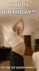 a man is dancing in a living room while wearing a white shirt and blue pants .