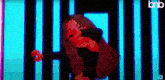 a cartoon girl is singing into a microphone while standing in front of a neon wall .