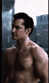 a shirtless man stands in front of a city