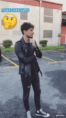 a man in a leather jacket is standing in a parking lot next to a building that says reservado