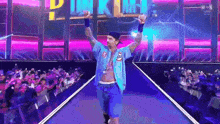 a man in a blue shirt and shorts is walking down a runway with his arms in the air .