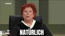 a judge is sitting in a courtroom with a drone in front of her and the word naturlich is written on the screen .