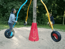 a man swings on a tire swing with a red cone in the middle