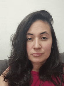 a woman with long dark hair is wearing a red top