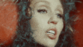 a close up of a woman 's face with blue feathers on her head
