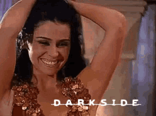 a woman is smiling with her hands in her hair and the word darkside is on the bottom of the image .
