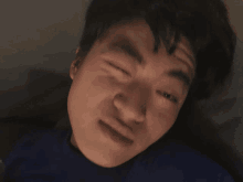 a man in a blue shirt is making a face with his eyes closed