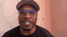 a man wearing glasses and a hat is smiling at the camera