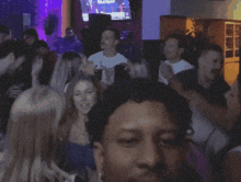 a blurry photo of a crowd at a party with a tv on the wall that says ' nfl ' on it