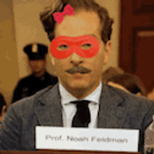 a man in a suit and tie with a red mask on his face