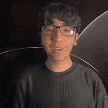 a young man wearing glasses and a black shirt looks at the camera