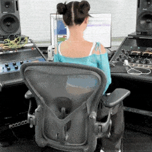 a woman in a blue top sits in a chair in front of a monitor that says ' poco ' on it