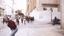 a woman with blue hair is laughing while walking down a city street