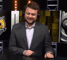 a man in a suit and headphones is smiling in front of a screen that says league