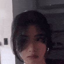 a close up of a woman 's face with a blurred background and earrings .