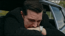 a man in a black suit is sitting in the back seat of a car .